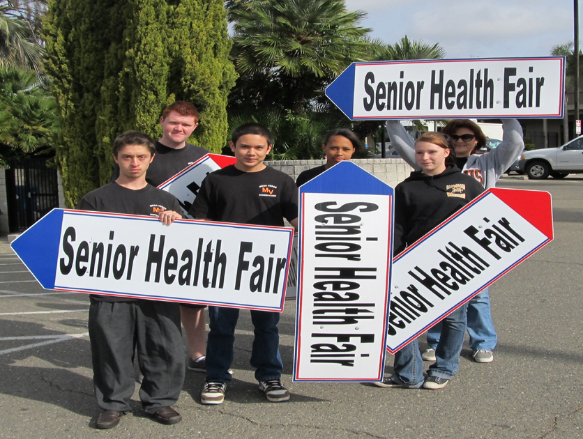 Volunteers holding Senior Health Fair directional signs